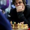 Un homme semble pensif devant un jeu d'échecs.