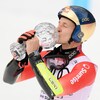 Le skieur Marco Odermatt embrasse un globe de cristal.