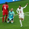 Le gardien, avec un air découragé, est à genou sur le gazon pendant qu'un joueur marocain célèbre son but. 