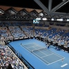 Vue générale d'un court intérieur de tennis pendant un match, avec quelques personnes dans les gradins