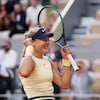 Une joueuse de tennis lève les bras et grimace de joie.