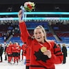Elle soulève un bouquet de fleurs sur la glace après un triomphe olympique.