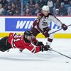 Un hockeyeur plonge devant un adversaire pour atteindre la rondelle.