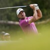Un golfeur termine son élan et regarde la balle. 