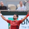 Un joueur de tennis lève les bras avec un air triomphant.