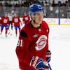 Un joueur de hockey en rouge sourit pendant un entraînement.