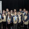 De nombreux athlètes posent fièrement, médaille au cou, devant une affiche de l'Outaouais