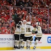 Quatre joueurs des Bruins célèbrent un but devant une foule de partisans déçus.