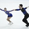 Un couple de patineurs artistiques sourit en patinant.