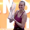 Une joueuse de tennis sourit et tient un trophée.