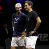 Les deux joueurs de tennis se regardent et sourient sur un terrain.