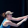 Une joueuse de tennis vêtue de bleu et portant une casquette noire frappe la balle du revers.