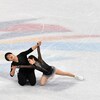 Un couple de patineurs artistiques est à genoux sur la glace pendant une performance.