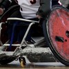 Un athlète amputé aux mains dirige un fauteuil usé.