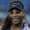 Serena Williams sourit sur un terrain de tennis.