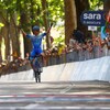 Le cycliste britannique, dans une combinaison bleue, file seul vers l'arrivée, les bras au ciel, alors que des partisans l'applaudissent, derrière des barricades. 