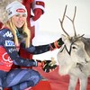 La skieuse sourit pendant qu'elle tente d'offrir du lichen à un renne.