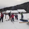 Des skieurs au pied d'une pente enneigée, devant un chalet de ski.