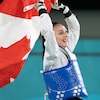 Deux taekwondoïstes font flotter le drapeau canadien au-dessus de leur tête.