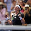 Une joueuse de tennis serre les poings et regarde en l'air en signe de victoire.