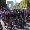 Un groupe de cyclistes amorcent un virage avec l'Arc de Triomphe en arrière-plan.