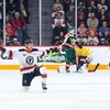 Joueur de hockey, agenouillé, les bras étendus, comme un oiseau qui déploie ses ailes.