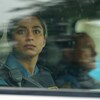 Une femme en uniforme regarde à travers la vitre d'une voiture.