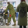 Un soldat pousse une personne en fauteuil roulant.