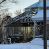 Une pelle mécanique procède à la démolition d'un bâtiment vitré en hiver.