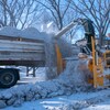 Une déneigeuse souffle dans un camion les bancs de neige et morceaux de glace le long d'une rue de Regina en hiver.