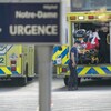 Des ambulanciers sortent un patient d'une ambulance devant une pancarte disant : Notre-Dame, urgence e