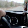 Une bouteille de bière sur un tableau de bord de voiture. 