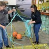 Deux employées démêlent une corde rattachée à une cage en métal.