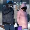 Des gens portent des masques à l'extérieur durant la pandémie de COVID-19 à Regina en hiver.