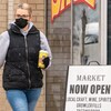 Une femme marche dans une rue de Saskatoon et porte un masque.