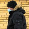Un homme au manteau noir porte un masque contre la COVID-19. 