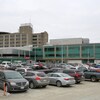 Un hôpital et un stationnement rempli de voitures. 