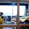 Une infirmière vêtue d'équipements de protection individuelle est dans la chambre d'un patient.