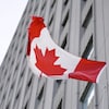 Le drapeau du Canada vogue devant l'édifice.
