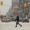 Un homme traverse une rue enneigée d'Ottawa.