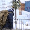 Une personne marche dans la rue sous la neige le jour. Elle porte un sac à dos d'expédition.
