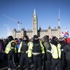Des policiers sont entourés de manifestants sur la colline du Parlement à Ottawa.