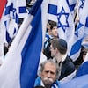 Des manifestants visibles entre les drapeaux israéliens.