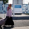 Une femme marche devant des affiches annonçant le prolongement de la ligne bleue du métro.