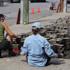 Deux citoyens enlèvent des pavés de béton sur la rue du Roi près d'une borne-fontaine.
