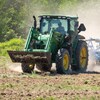 Un cultivateur sur un tracteur dans un champ.