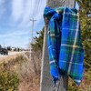 Tartan bleu et vert noué à un poteau le long d'une route rurale.