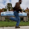 Un homme passe en courant devant l'enseigne du campus de Moncton.