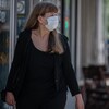 Une femme portant le masque marche sur le trottoir.