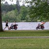 Un piéton et deux personnes en scooter portant un masque au bord d'un lac.